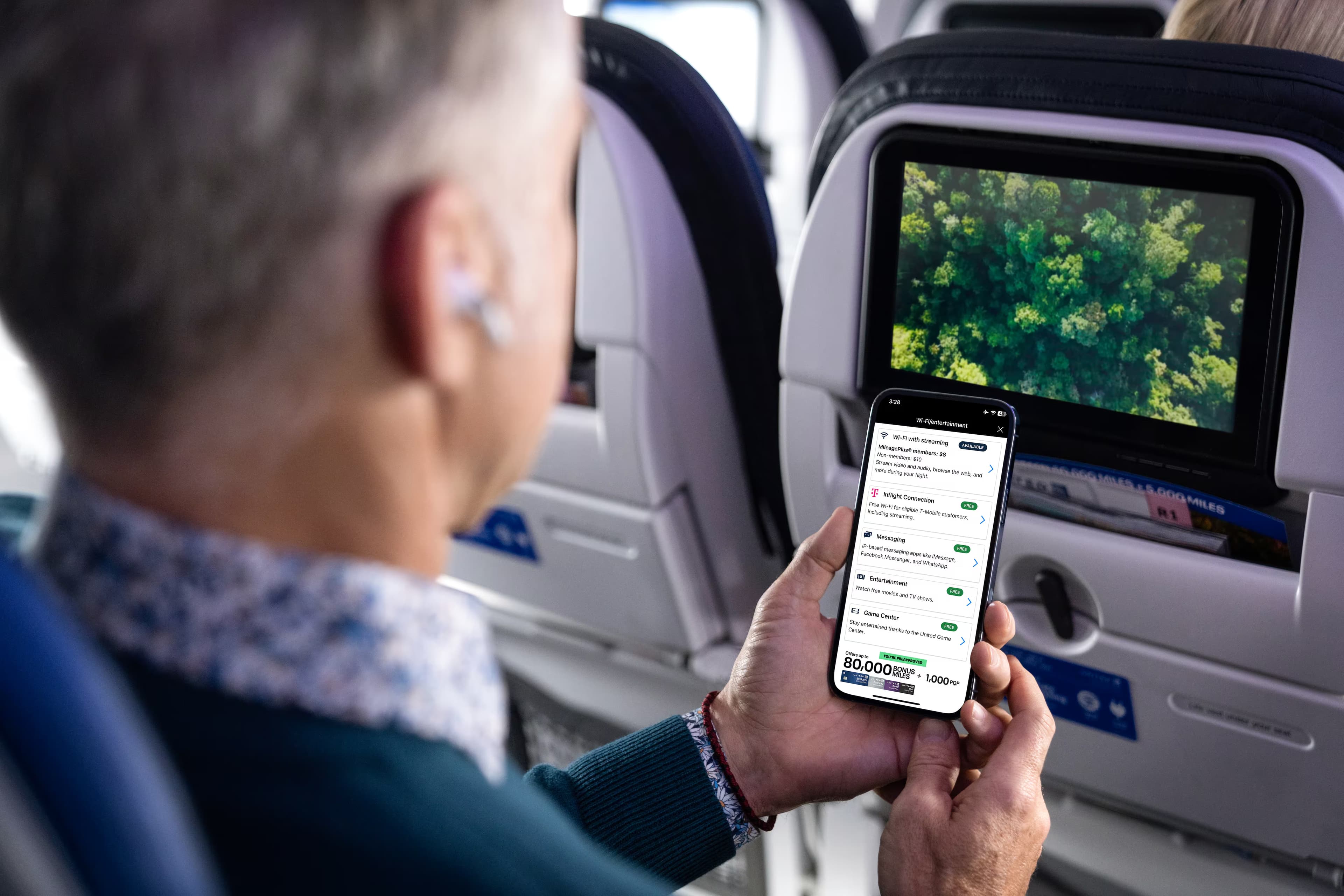 man looks at his phone on a flight